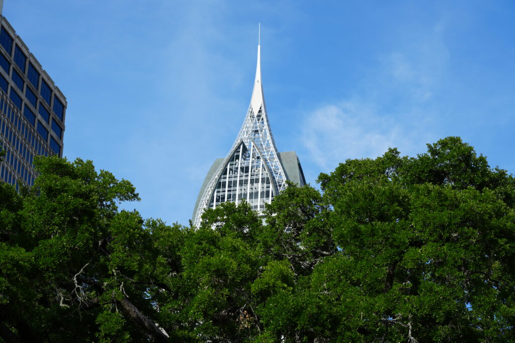 The crystalline spire of the RSA Battle House Tower above live oaks