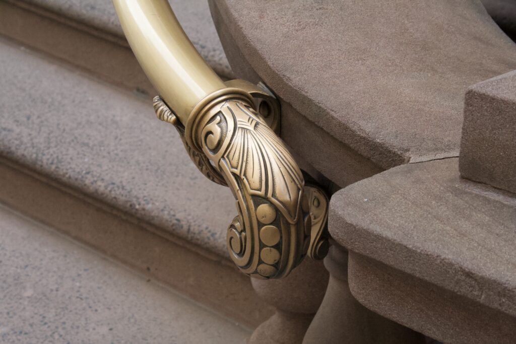 Ornate cast brass handrail detail against stone steps