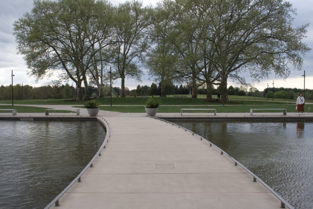 A curving boardwalk crossing still water toward bare spring trees