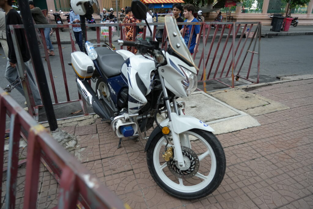 A white scooter behind red steel barriers on a city sidewalk