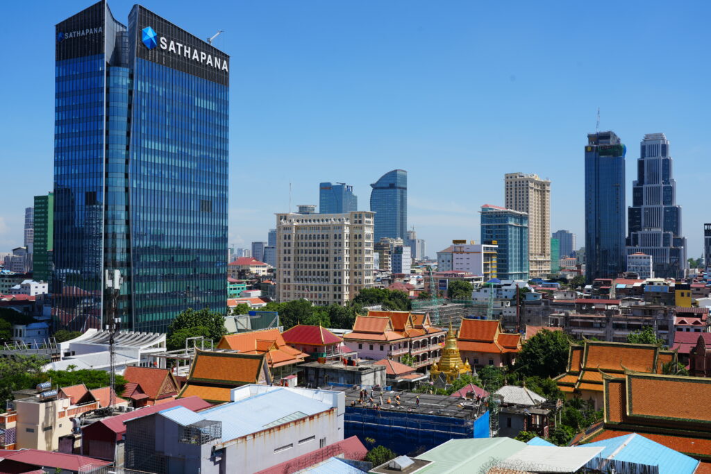 Glass towers rising behind the tiled roofs of a temple complex