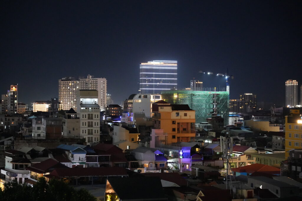 Lit high-rises above a dense low-rise neighbourhood after dark