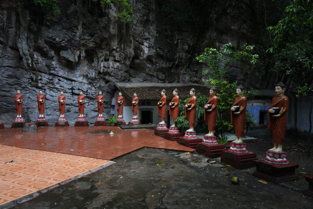 A row of robed Buddha statues in a limestone cave shrine