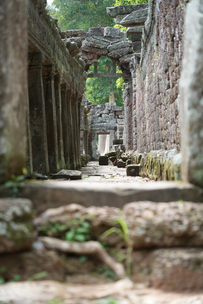 Carved blocks scattered along a ruined temple corridor