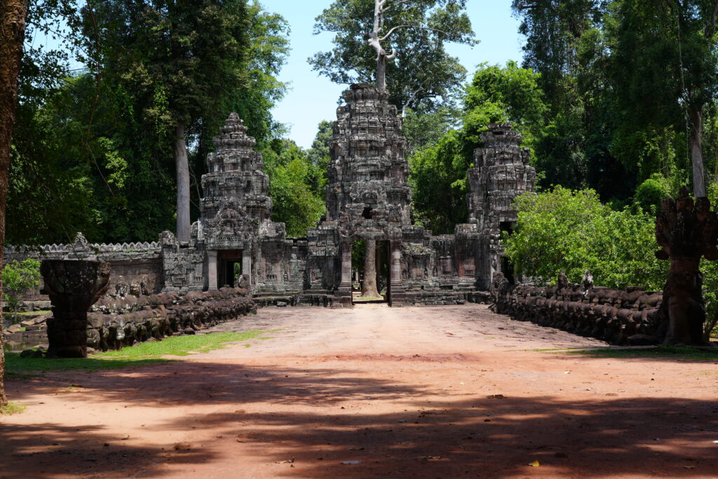 A red earth causeway leading to a carved stone temple gate
