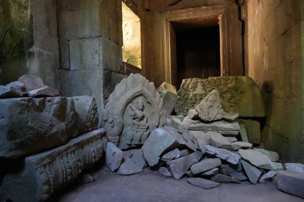 Carved relief fragments stacked in a sunlit stone doorway