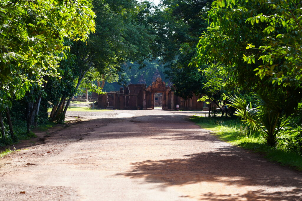 A red dirt road running straight to a distant temple gate