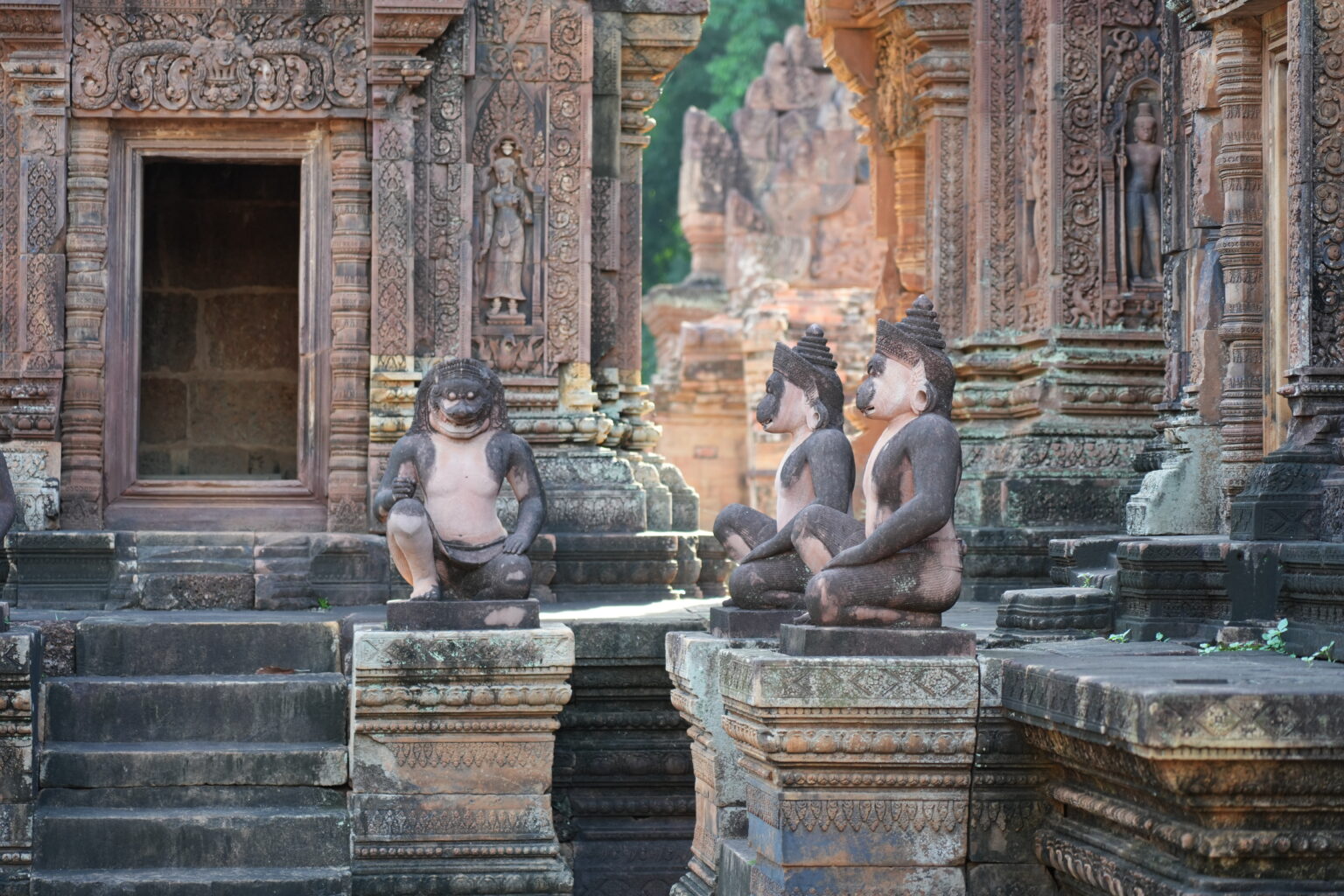 Kneeling guardian figures before the deeply carved temple wall