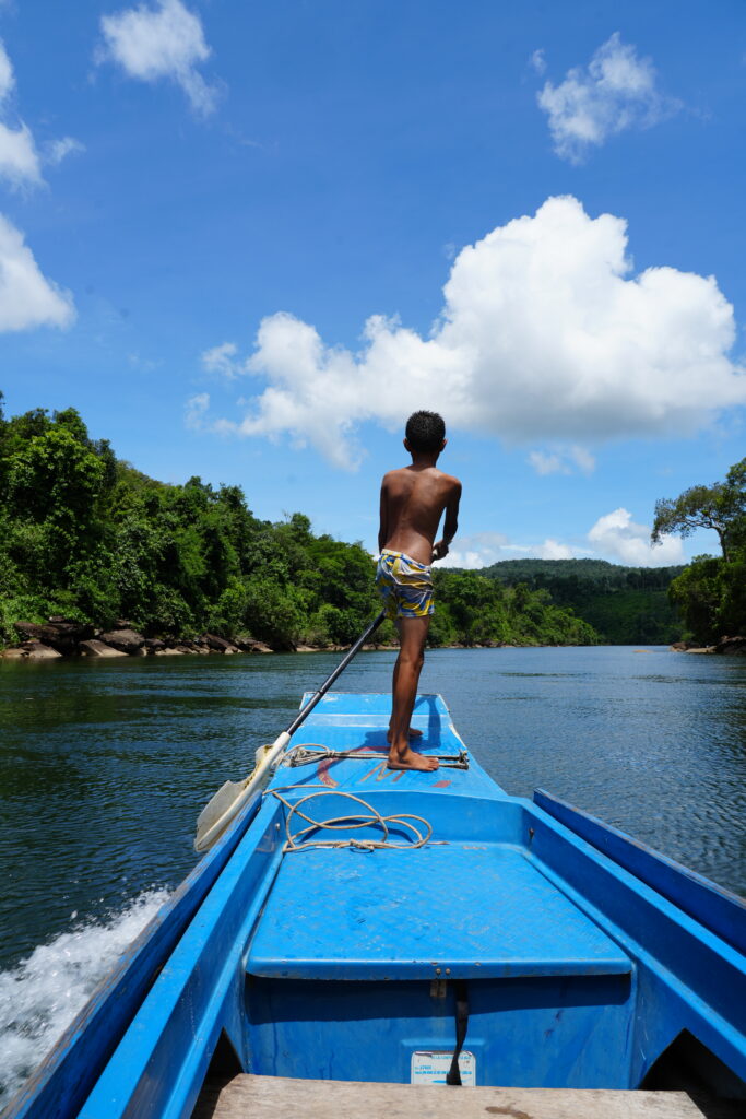 Boy at boat bow, jungle river