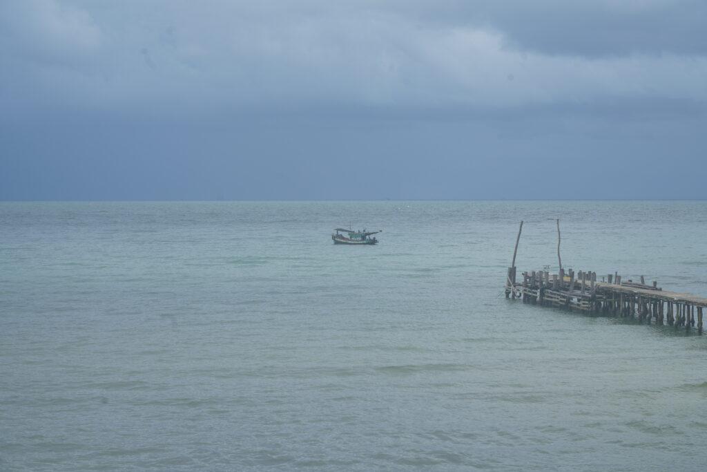 Distant pier and boat, dark sky