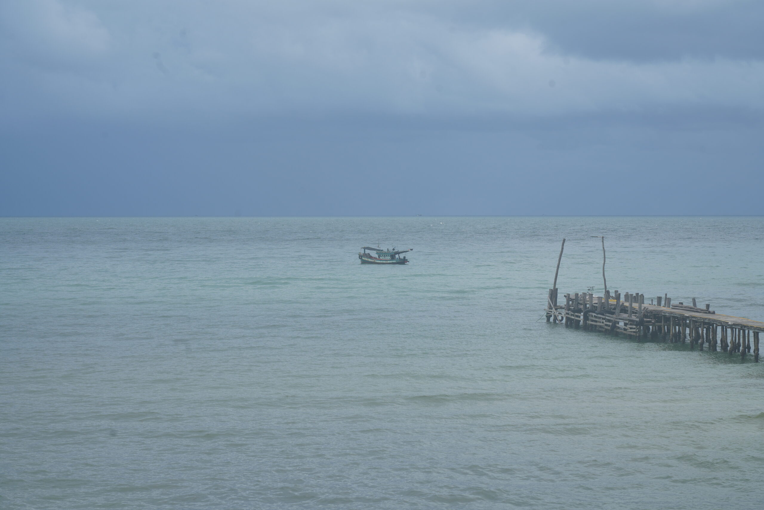 Distant pier and boat, dark sky