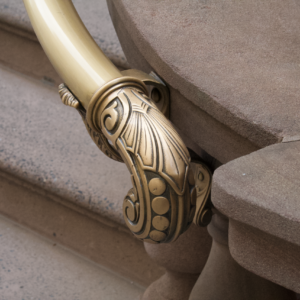 Ornate cast brass handrail detail against stone steps