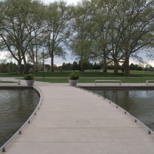 A curving boardwalk crossing still water toward bare spring trees