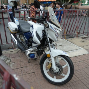 A white scooter behind red steel barriers on a city sidewalk