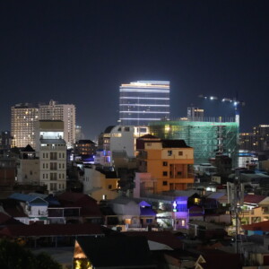 Lit high-rises above a dense low-rise neighbourhood after dark
