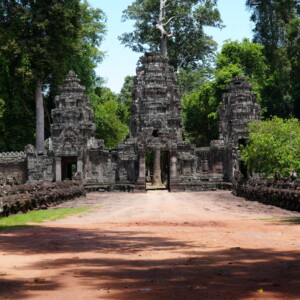 A red earth causeway leading to a carved stone temple gate