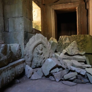 Carved relief fragments stacked in a sunlit stone doorway