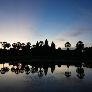 Angkor Wat silhouetted against deep blue dawn and mirrored in water